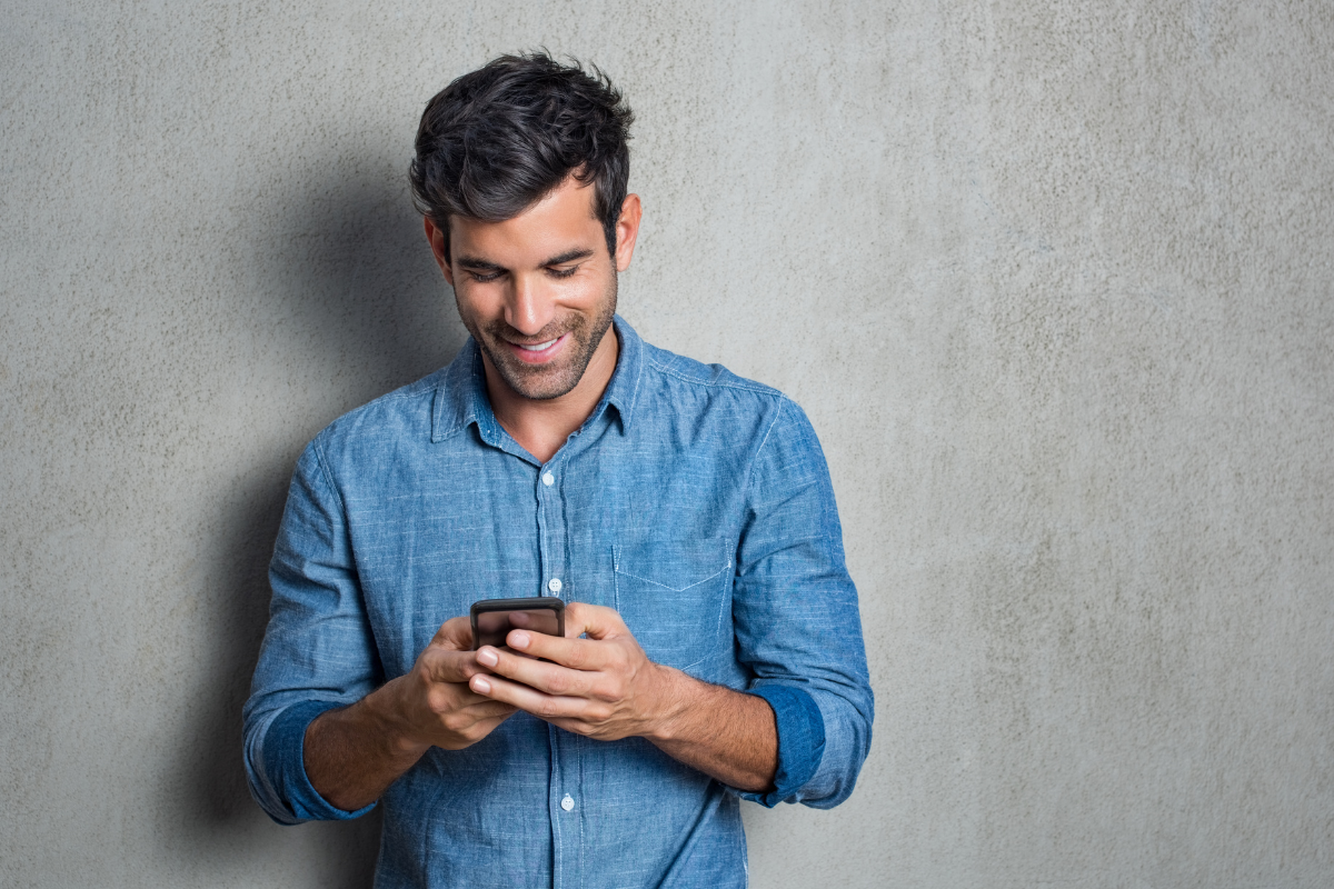 Hombre sonriendo mientras usa el celular para enviar dinero de Chile a México con el Dulloo