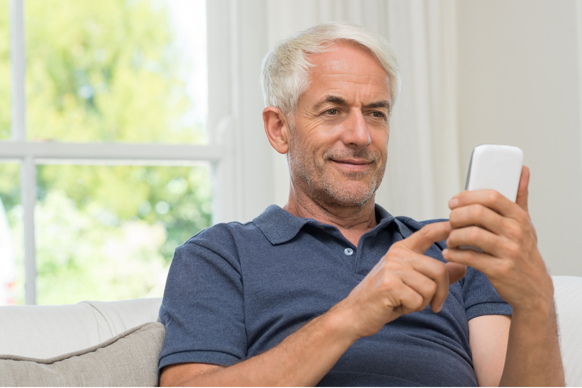 Homem sorrindo enquanto usa o celular para enviar dinheiro do Brasil para a Argentina com o Dulloo